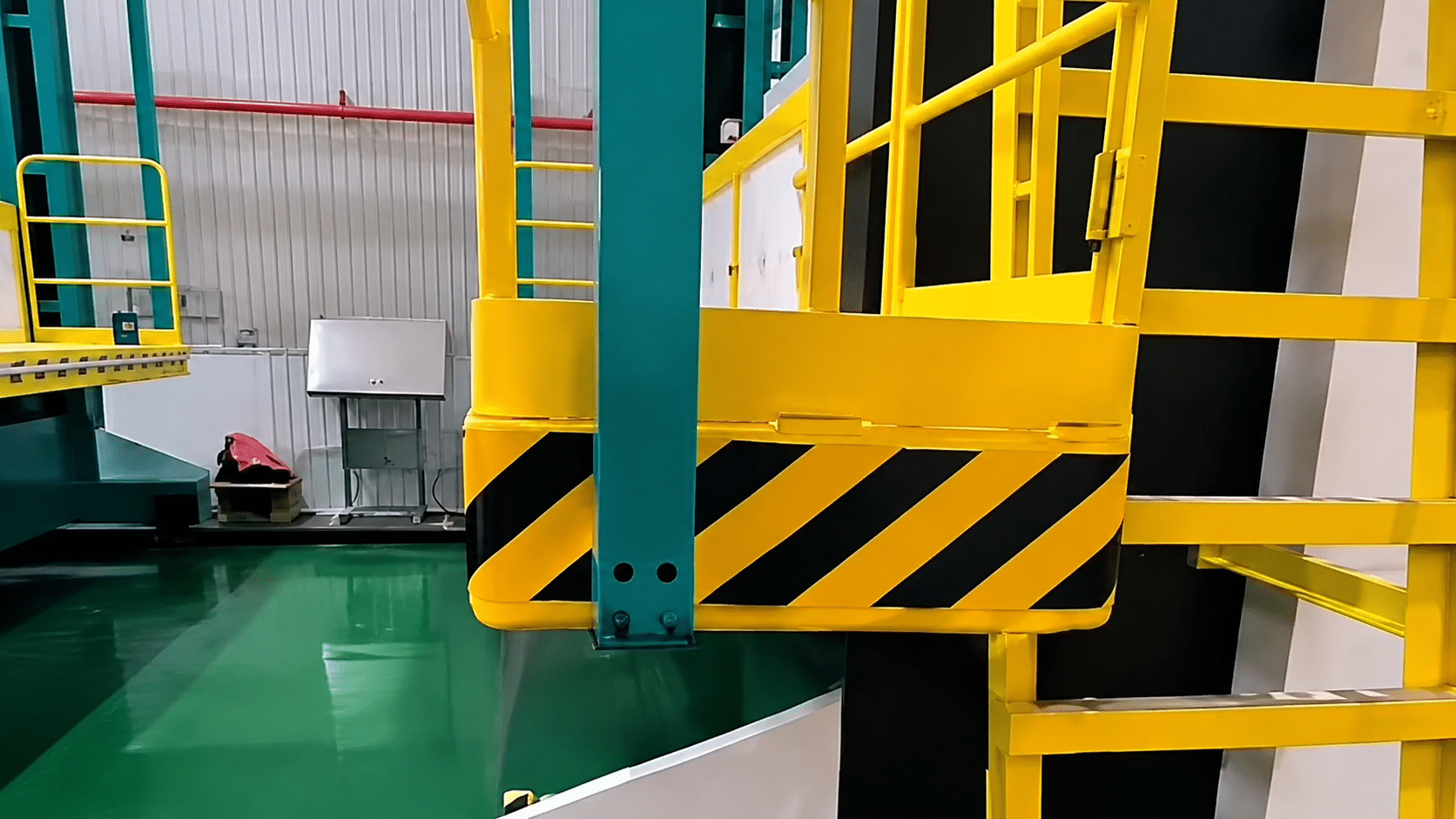 A yellow assembly platform with safety railings and black-yellow striped warning edges