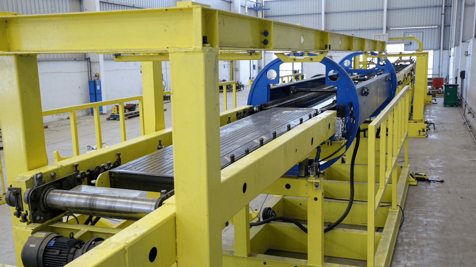 The bilateral seam welding section with its blue frames, adjustable handwheels and chain conveyor