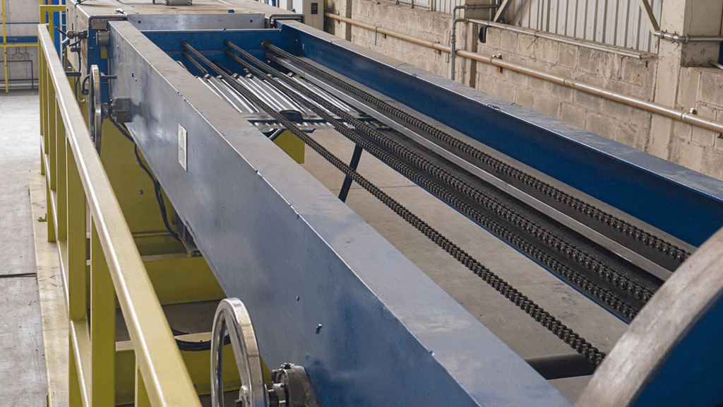 Transfer conveyor between the forming and welding stations with manual width-adjustment handwheels