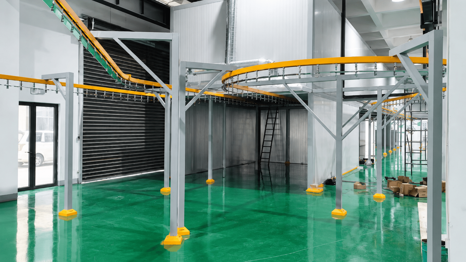Overhead conveyor return loop at the load and unload station of an industrial painting line