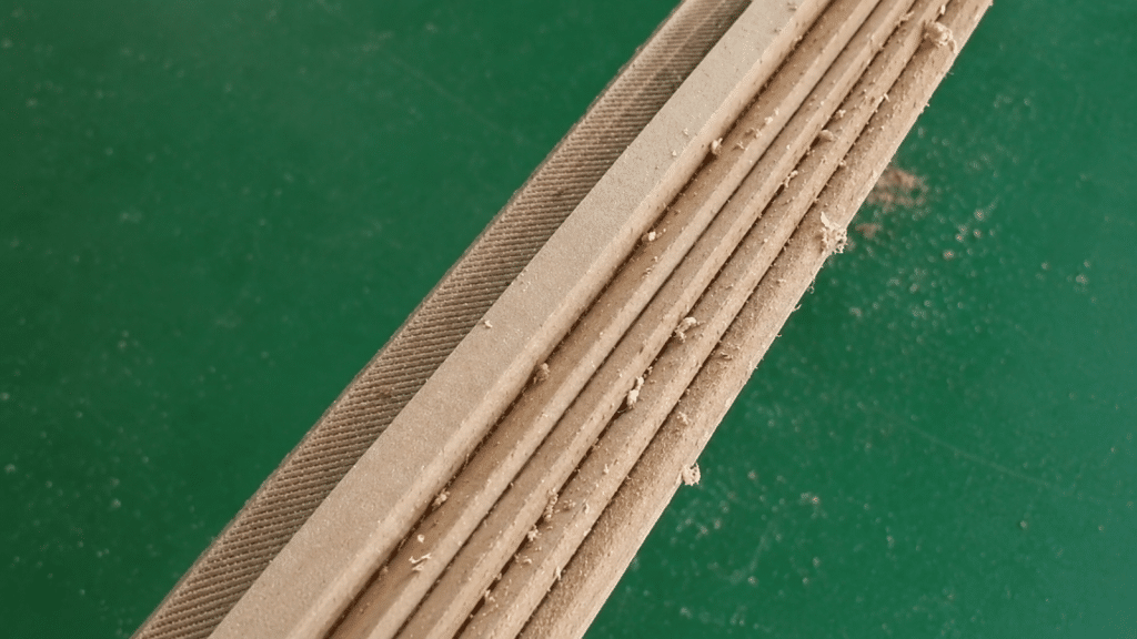 Multiple strips shaping machine output — beveled transformer cooling duct strips cut from pressboard, burr-free edges